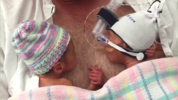 Cute Twins Holding Hands on Their Father’s Chest